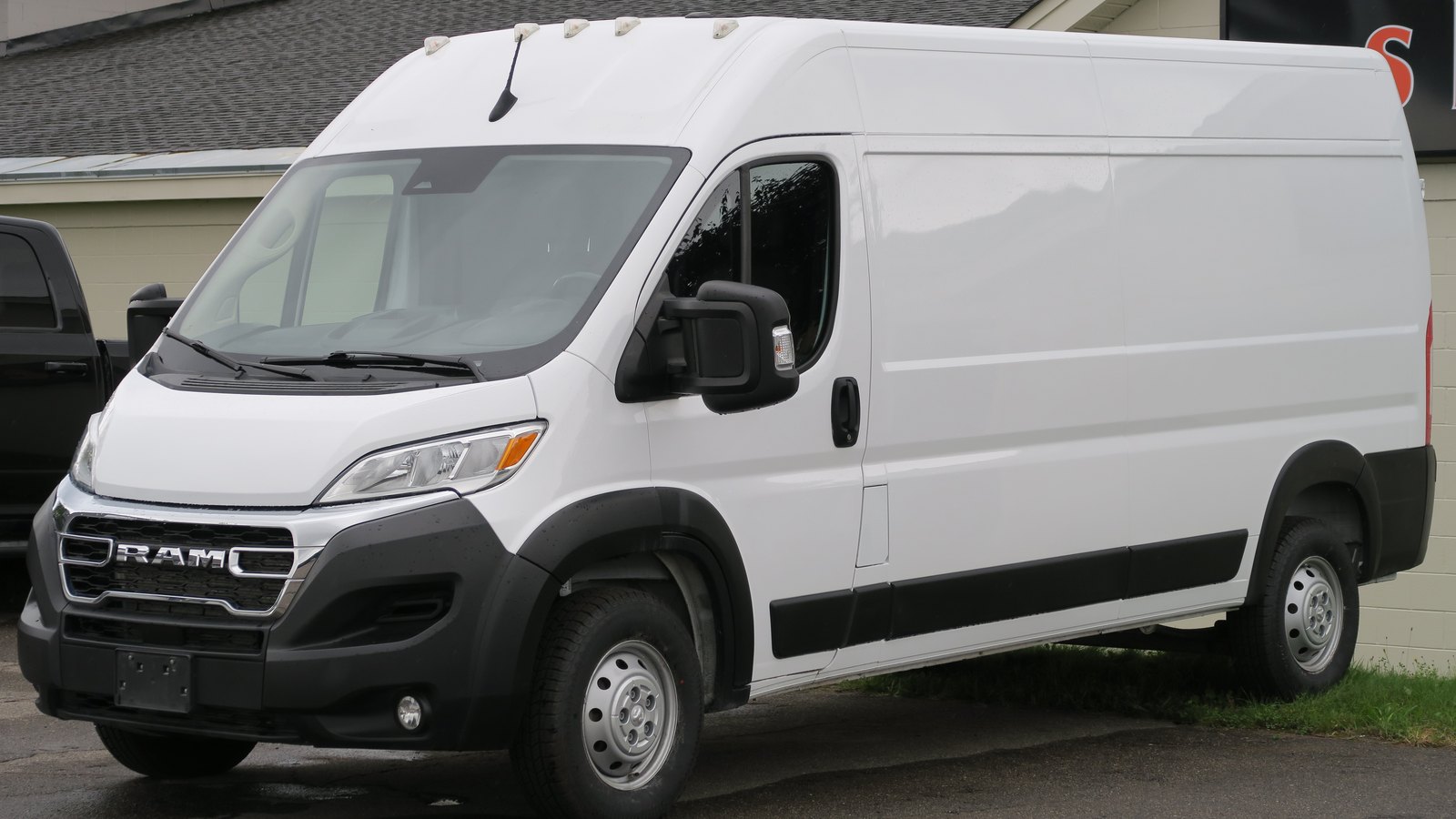 Camioneta de carga Ram ProMaster 2500 2023 blanca de techo alto estacionada frente a un edificio, vista desde el frente a la izquierda