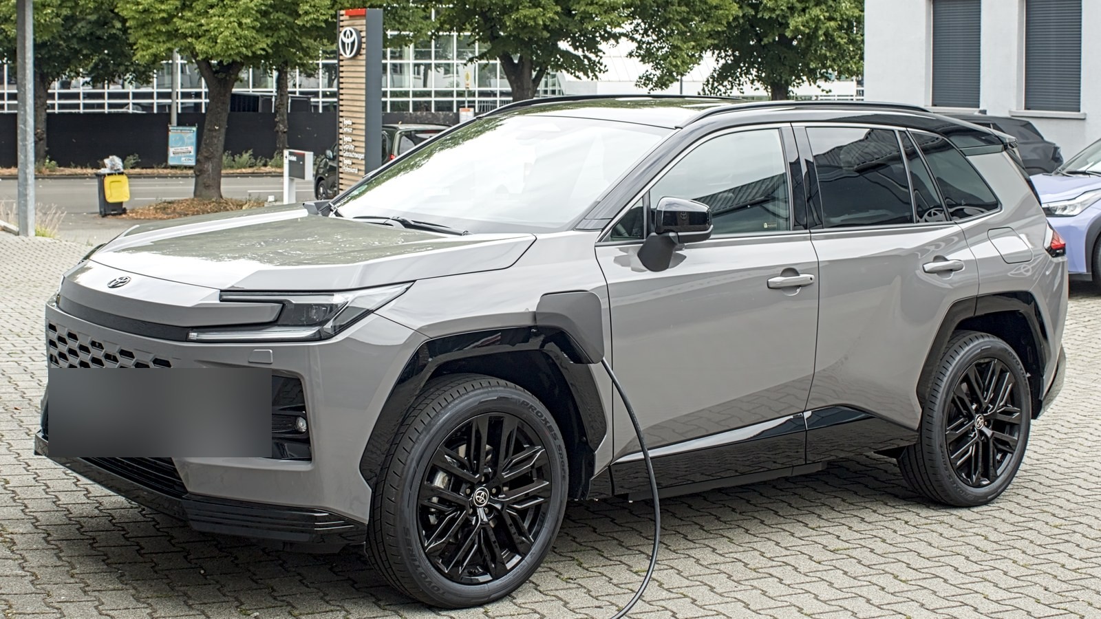 Crossover Toyota RAV4 Core Plug-in Hybrid gris, visto desde el frente izquierdo, con cable de carga conectado