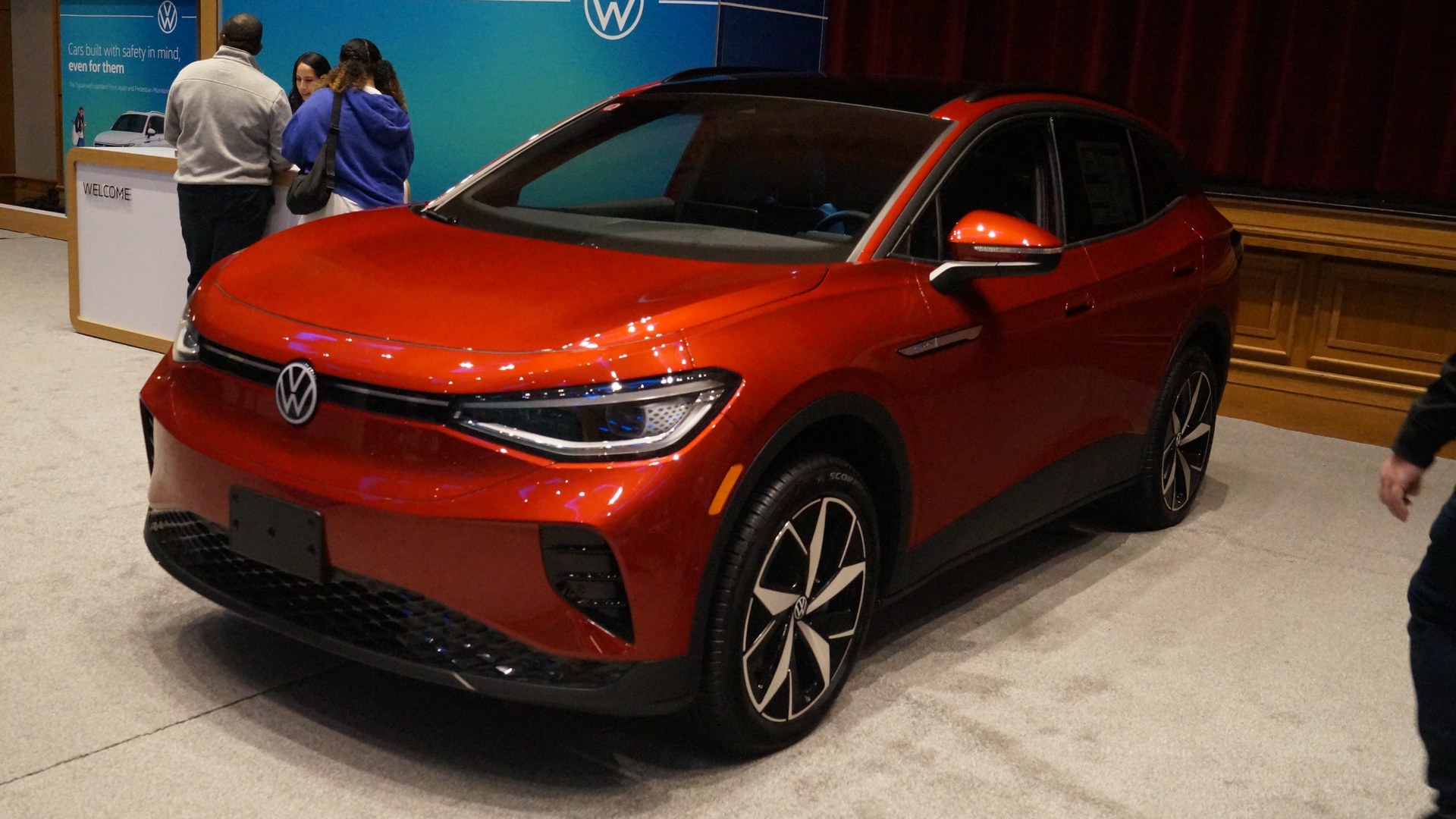 SUV eléctrico Volkswagen ID.4 rojo en exhibición bajo techo, visto desde el frente izquierdo